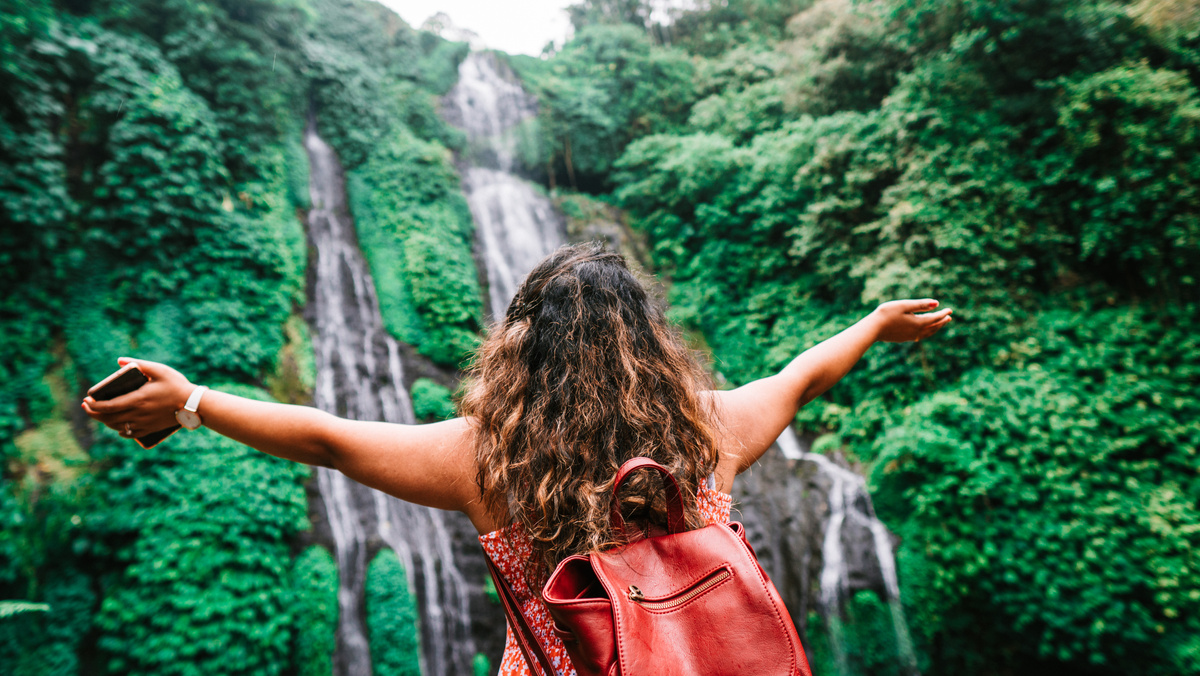Anonymous female traveler admiring amazing waterfall
